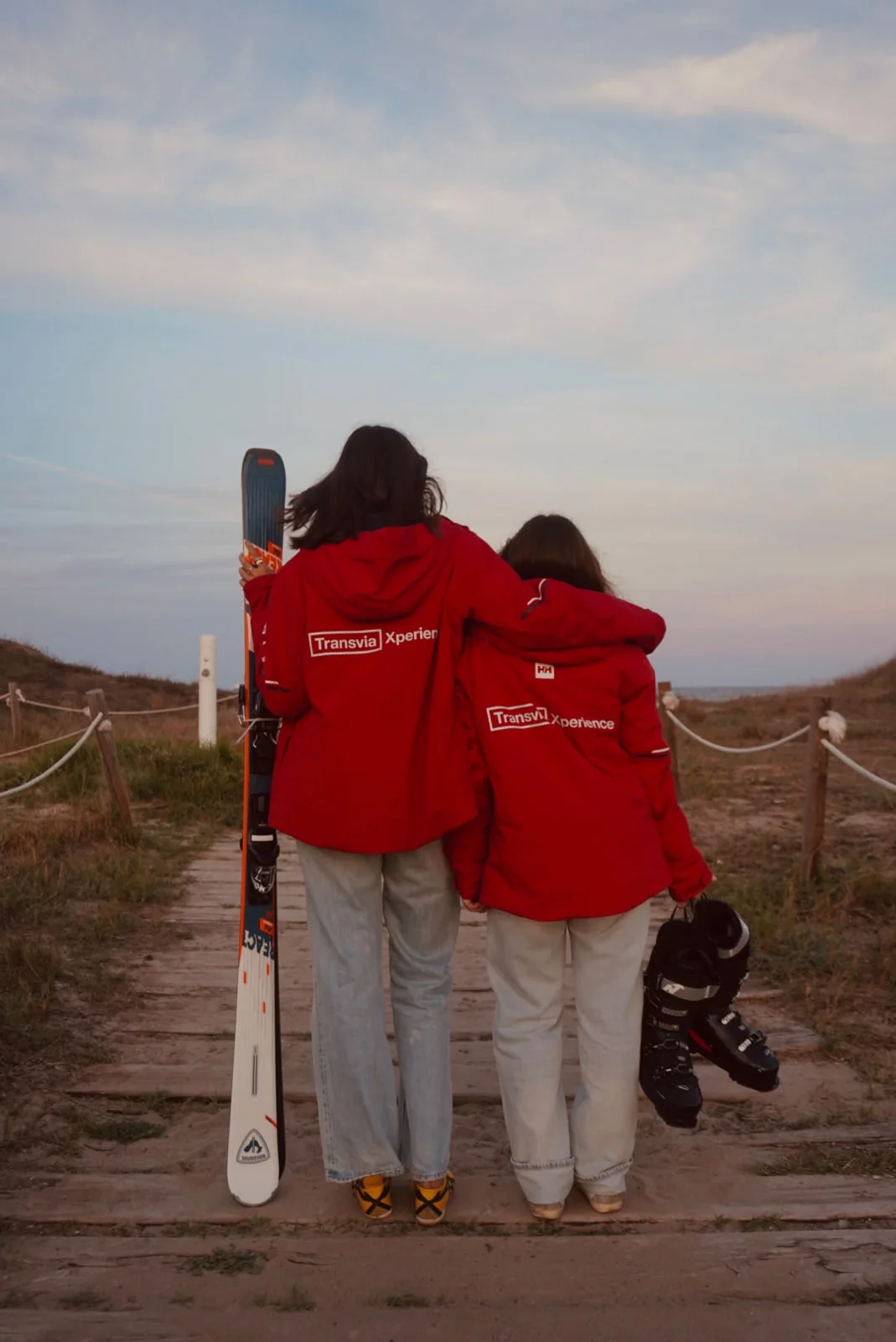 Las dos protagonistas con las chaquetas rojas de Transvia y los esquís en la pasarela de la playa